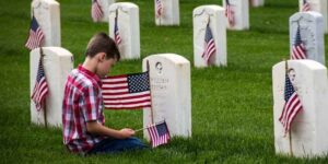 Memorial Day: gone but not forgotten - boy placing flag on grave at Arlington Cemetery